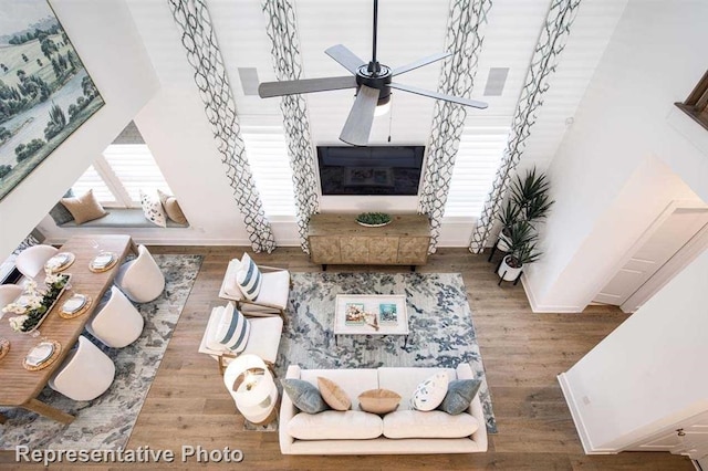 living area featuring wood finished floors, visible vents, baseboards, and ceiling fan