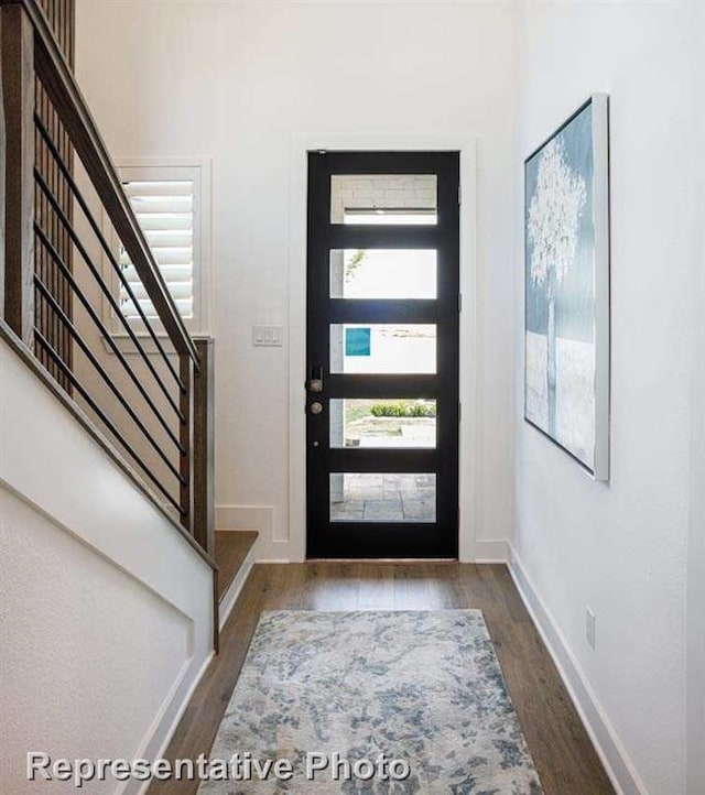 entryway featuring wood finished floors, baseboards, and stairway