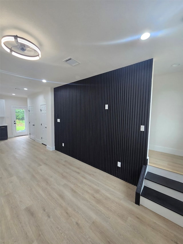 unfurnished room featuring visible vents, baseboards, an accent wall, and light wood-style floors