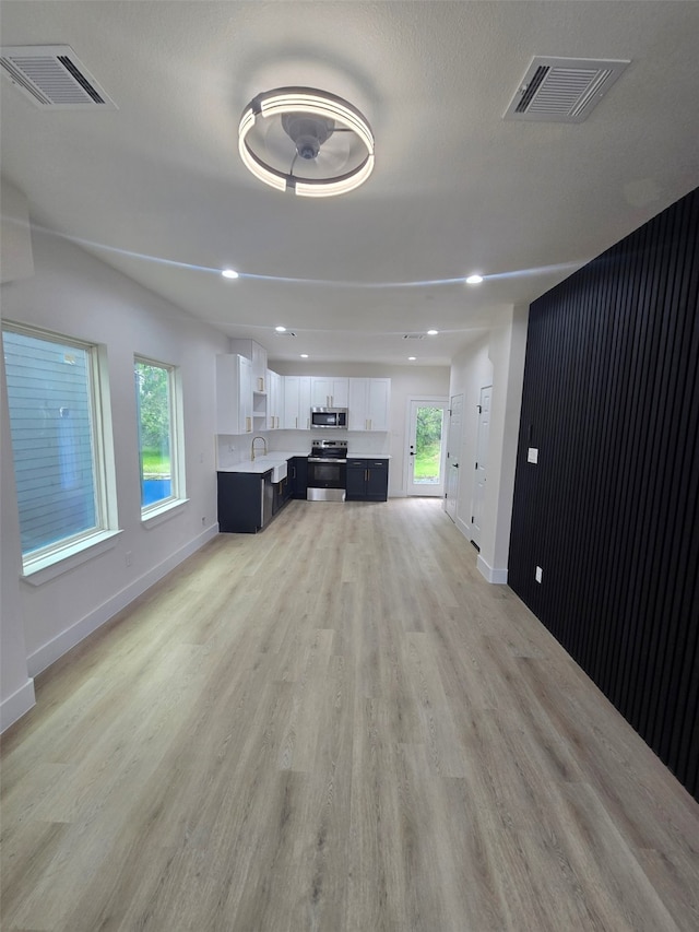 living area featuring light wood finished floors, baseboards, visible vents, and a wealth of natural light