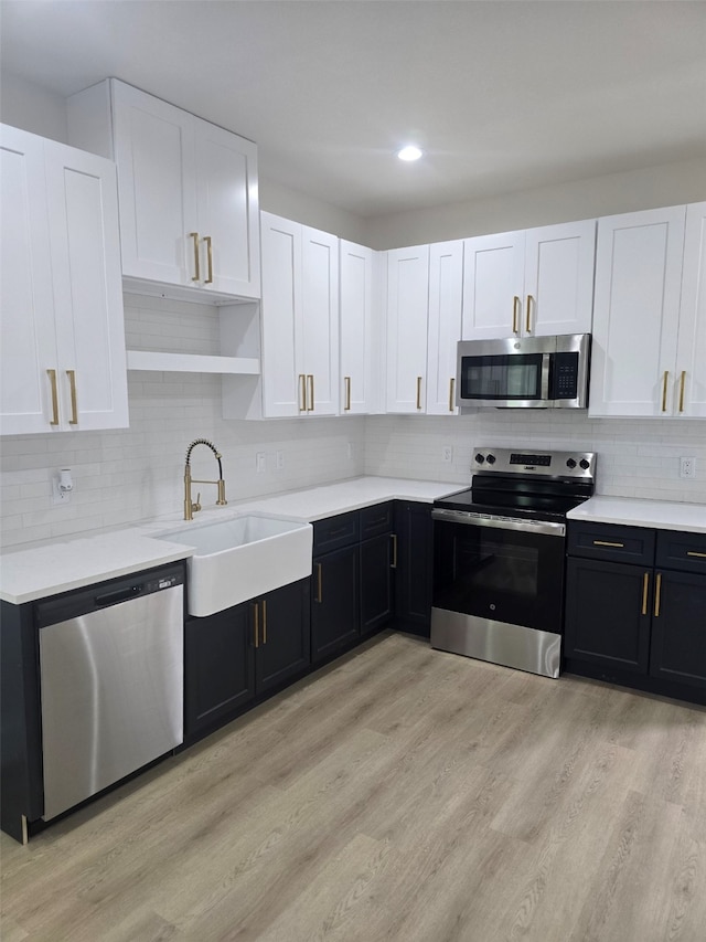 kitchen featuring white cabinets, stainless steel appliances, light countertops, and a sink