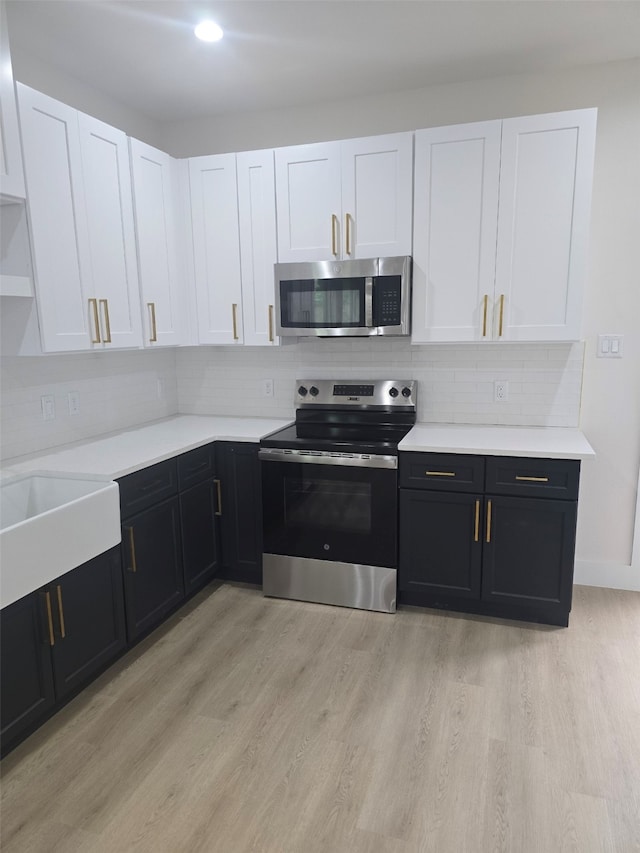 kitchen with light wood-style floors, appliances with stainless steel finishes, and white cabinetry