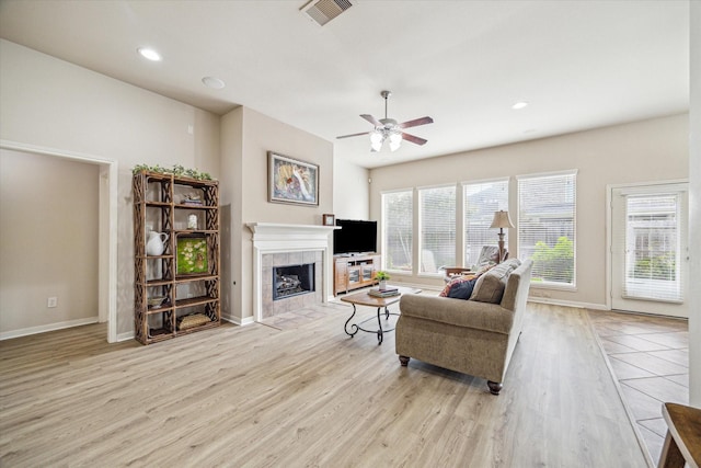 6315 Teal Mist Ln, Fulshear, TX 77441 - living room featuring a ceiling fan, visible vents, a tile fireplace, baseboards, and light wood-style flooring