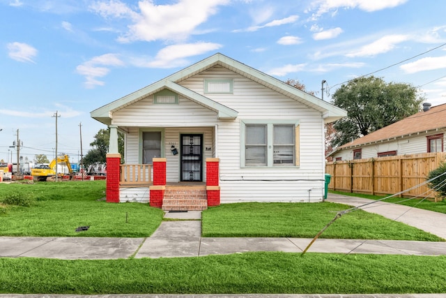 bungalow-style house with a porch, a front yard, and fence