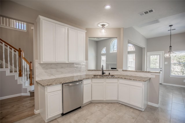 kitchen with stainless steel dishwasher, light stone counters, a sink, white cabinets, and visible vents