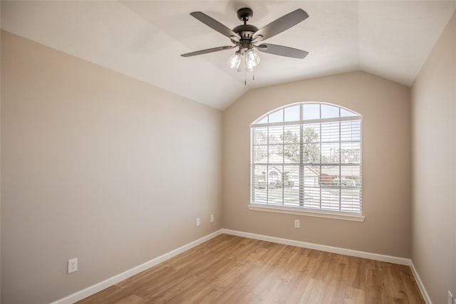 spare room with light wood finished floors, a ceiling fan, baseboards, and lofted ceiling