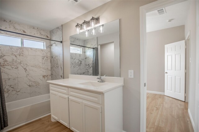 bathroom featuring wood finished floors, visible vents, shower / bath combination, and vanity
