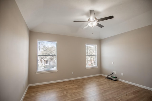spare room with lofted ceiling, baseboards, wood finished floors, and ceiling fan