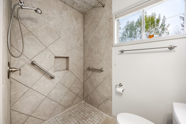 bathroom featuring a tile shower and toilet