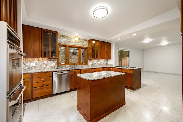 3622 N Braeswood Blvd, Houston, TX 77025 - kitchen with stainless steel appliances, a peninsula, a tray ceiling, a center island, and light stone countertops