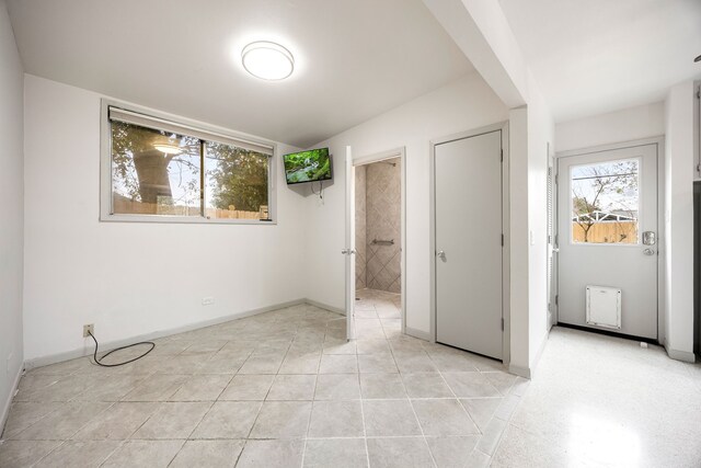 unfurnished bedroom featuring baseboards, connected bathroom, and multiple windows