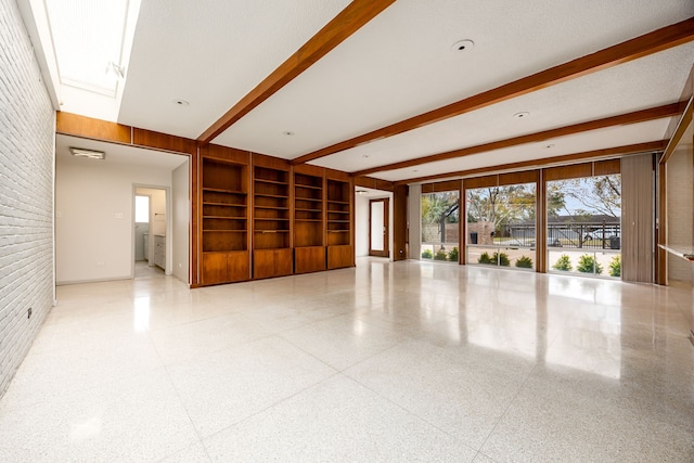 unfurnished room featuring speckled floor, built in features, and beamed ceiling