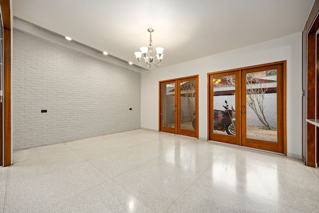 3622 N Braeswood Blvd, Houston, TX 77025 - unfurnished room with french doors, brick wall, a chandelier, speckled floor, and baseboards