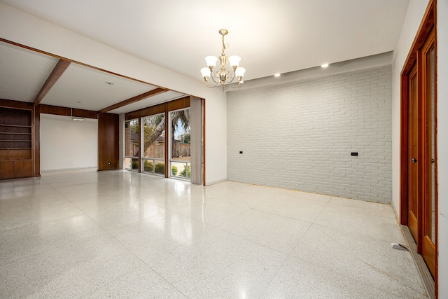 unfurnished room featuring beamed ceiling, brick wall, baseboards, and a notable chandelier