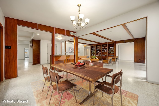 3622 N Braeswood Blvd, Houston, TX 77025 - dining area with dark speckled floor, a chandelier, wooden walls, and baseboards