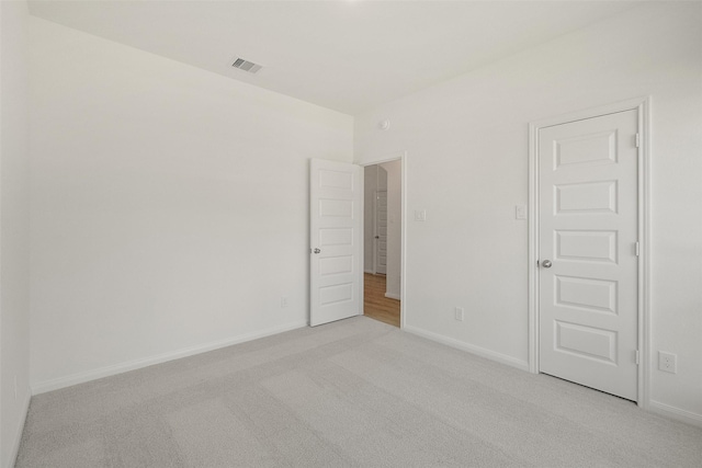 empty room featuring light carpet, baseboards, and visible vents