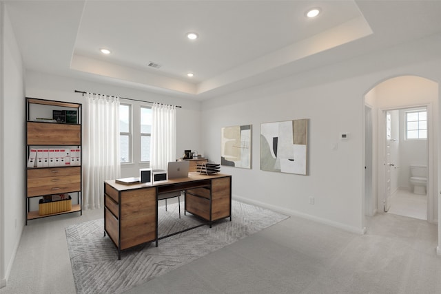 office area with plenty of natural light, visible vents, arched walkways, and a raised ceiling