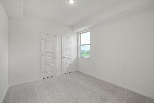 spare room with baseboards and light colored carpet