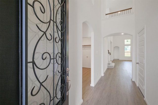 foyer with baseboards, wood finished floors, and arched walkways