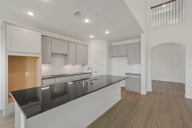 kitchen featuring a sink, light wood-type flooring, visible vents, decorative backsplash, and gray cabinetry