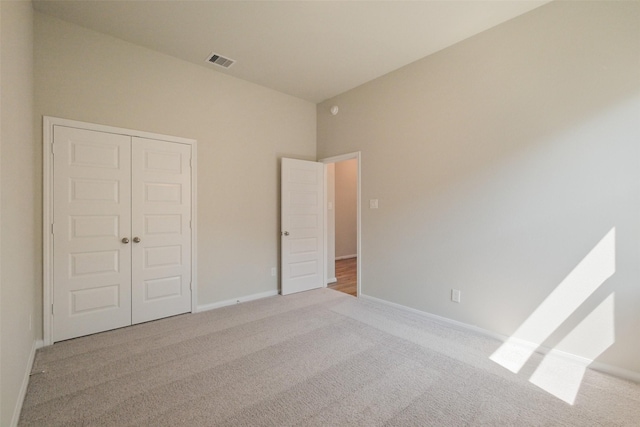 unfurnished bedroom featuring baseboards, visible vents, carpet floors, and a closet