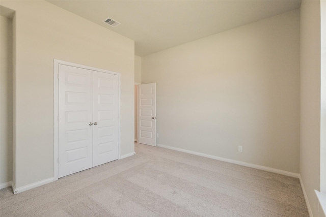 unfurnished bedroom featuring light colored carpet, baseboards, and a closet