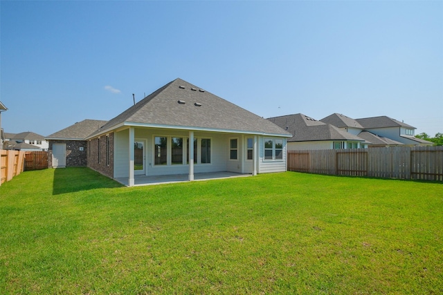 rear view of house featuring a fenced backyard, a yard, a patio, and a shingled roof