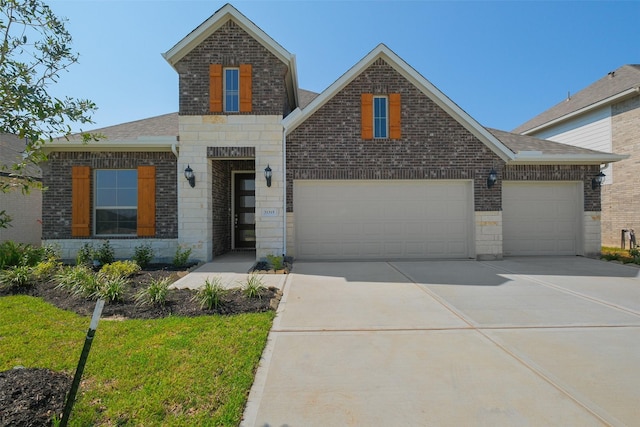 traditional home with stone siding, concrete driveway, brick siding, an attached garage, and a shingled roof