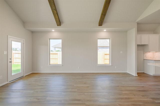 unfurnished living room featuring a wealth of natural light, light wood finished floors, and baseboards