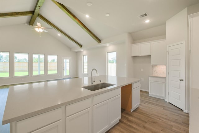 kitchen with a sink, an island with sink, ceiling fan, white cabinetry, and visible vents