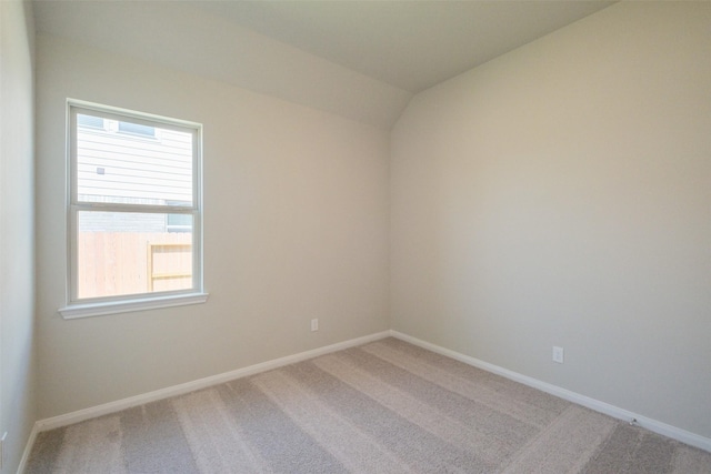 carpeted spare room with lofted ceiling and baseboards