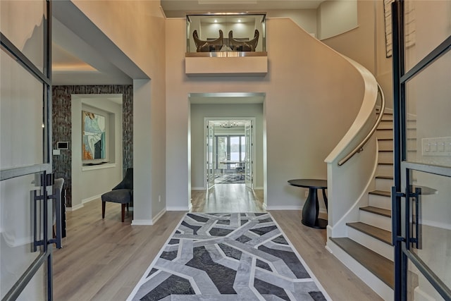 entryway featuring baseboards, wood finished floors, a towering ceiling, and stairs