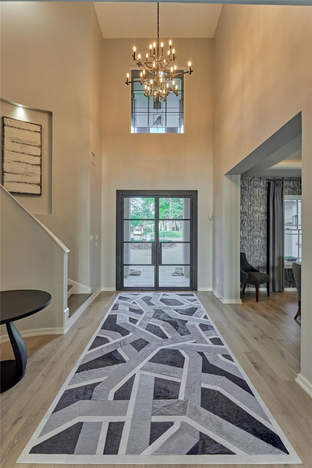 foyer featuring baseboards, wood finished floors, an inviting chandelier, and stairs