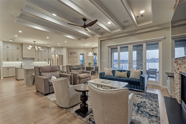 living area with light wood finished floors, a fireplace, recessed lighting, and ceiling fan with notable chandelier