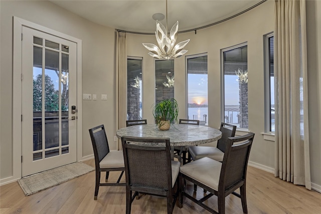 dining space with a chandelier, light wood-style floors, a healthy amount of sunlight, and baseboards