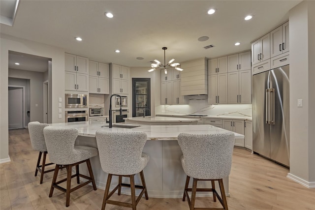 kitchen with a large island with sink, visible vents, a chandelier, appliances with stainless steel finishes, and custom range hood