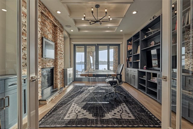 office area featuring recessed lighting, a stone fireplace, light wood-style floors, built in features, and a notable chandelier