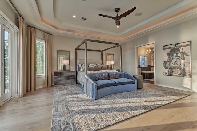 bedroom with light wood finished floors, baseboards, visible vents, connected bathroom, and a raised ceiling