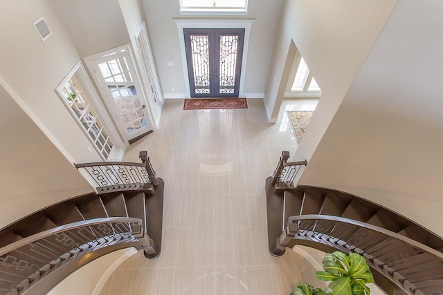 tiled entrance foyer with baseboards, visible vents, french doors, and a towering ceiling