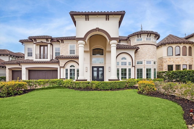 mediterranean / spanish home with a tile roof, stucco siding, french doors, a front lawn, and a garage