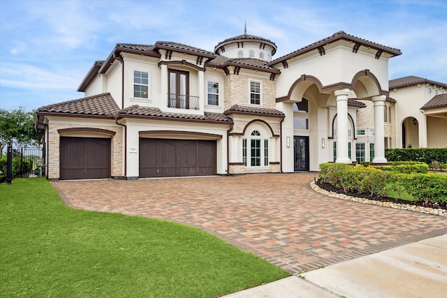mediterranean / spanish house featuring stone siding, decorative driveway, french doors, and a tiled roof