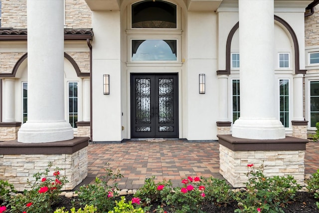 view of exterior entry with stucco siding, french doors, and stone siding