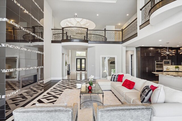 living area featuring baseboards, recessed lighting, a chandelier, and a high ceiling