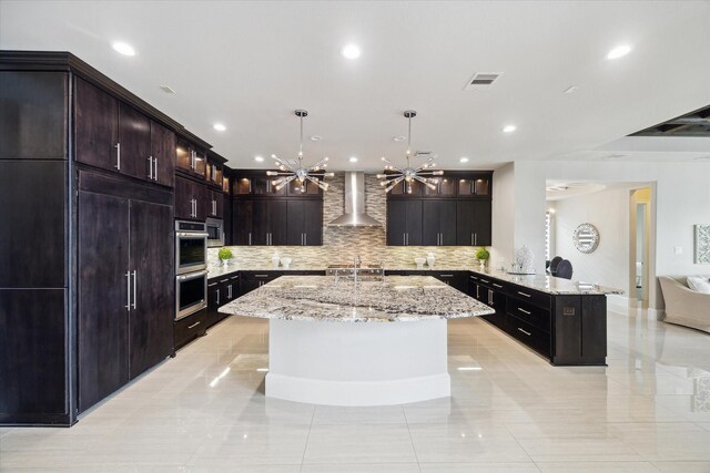 kitchen with tasteful backsplash, appliances with stainless steel finishes, visible vents, wall chimney exhaust hood, and a peninsula