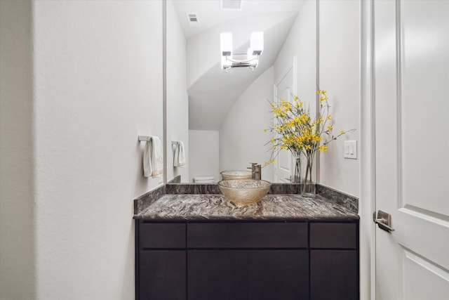 half bathroom with visible vents, lofted ceiling, and vanity