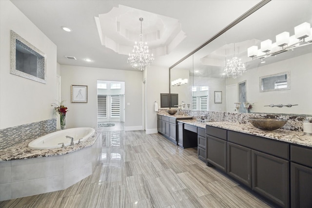 full bathroom featuring a sink, a raised ceiling, visible vents, an inviting chandelier, and a bath