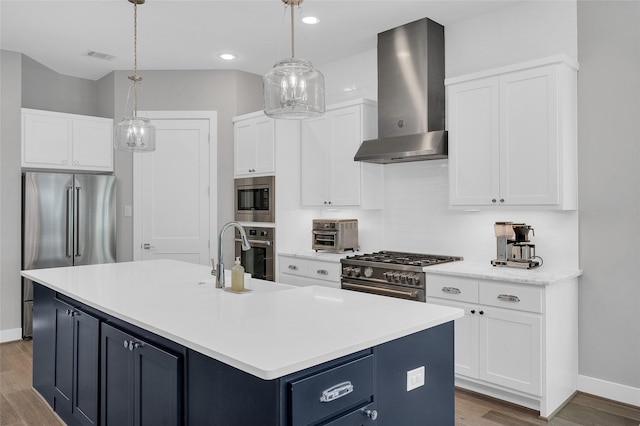 kitchen with high end appliances, wall chimney exhaust hood, backsplash, light countertops, and wood finished floors