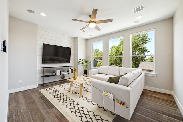 living room with baseboards, visible vents, wood finished floors, and a ceiling fan