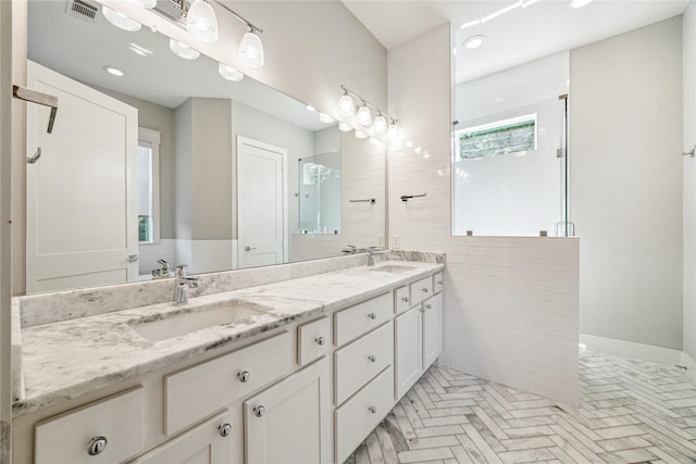 bathroom with visible vents, a stall shower, double vanity, and a sink