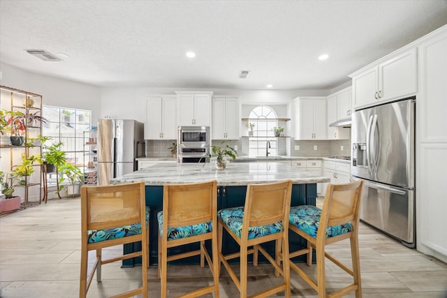 kitchen with backsplash, white cabinetry, a center island, and stainless steel appliances